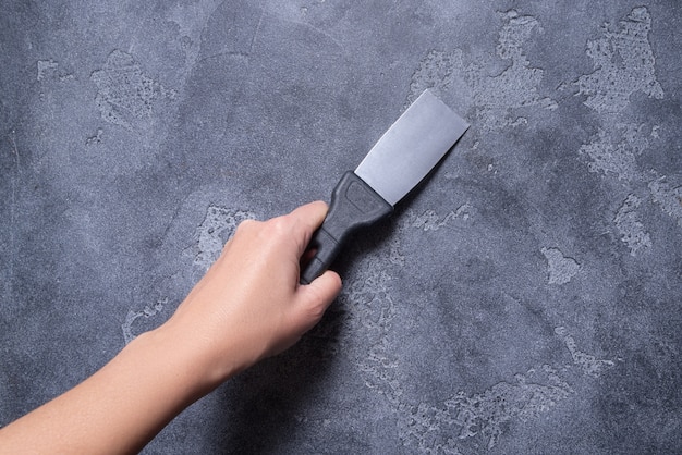 Hand with  putty knifes on grey background