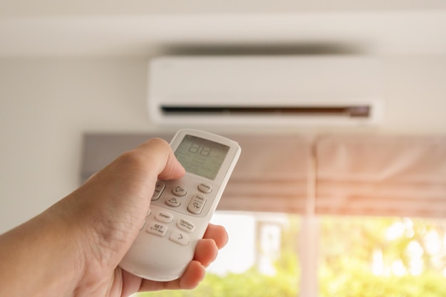 Photo hand with remote control directed on air conditioner