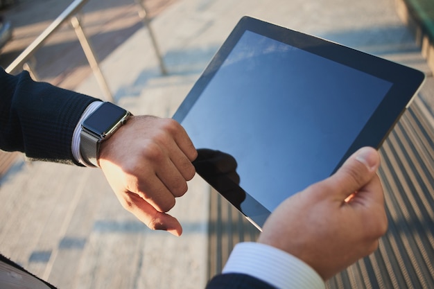 Hand with smart watch and a hand holding the tablet