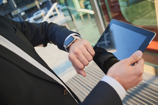 Hand with smart watch and a hand holding the tablet