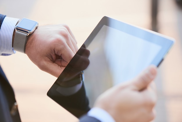 Hand with smart watch and a hand holding the tablet