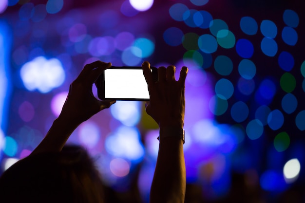 Hand with a smartphone records luxury party with blank white screen