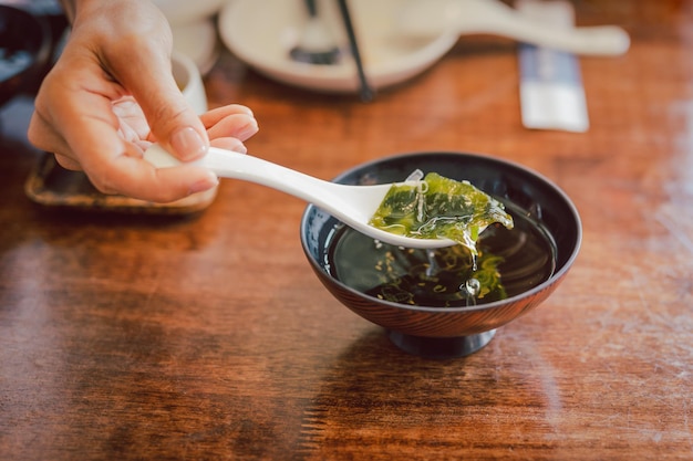 伝統的な海藻の日本のスープを食べるスプーンで手