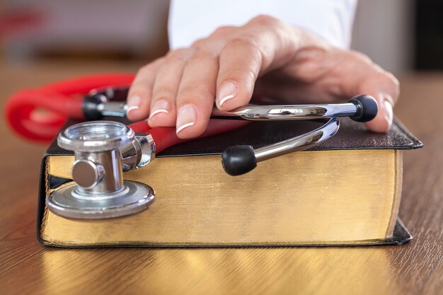 hand with stethoscope on top of old book