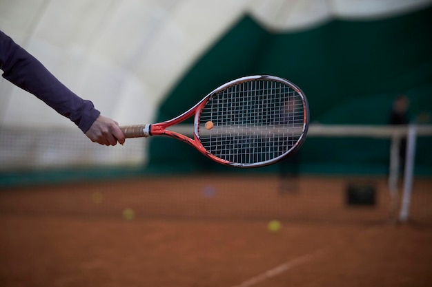 hand with a tennis racket on the background of a tennis court A tennis player holding the racket