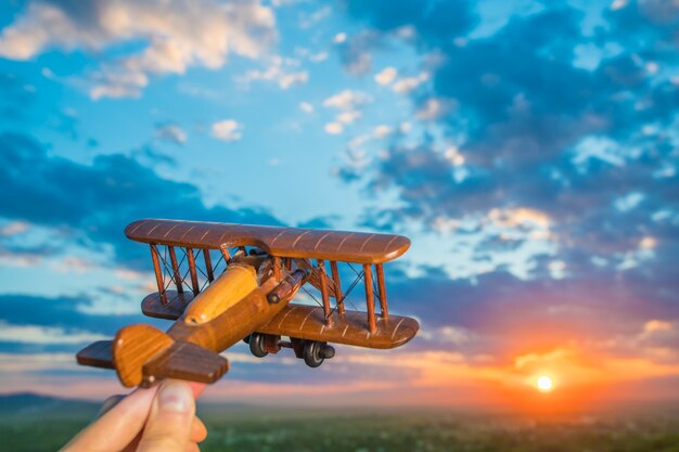 The hand with a toy airplane against the background of a sunset