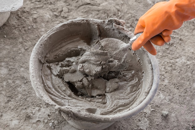 Photo hand with trowel and bucket with mortar at consturction site