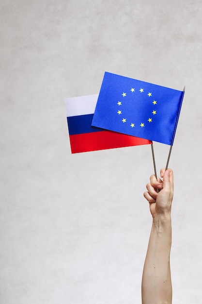 A hand with two flags- EU and Russia. Free space for a text