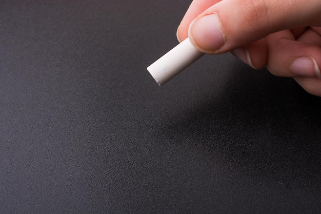 Hand with white chalk and black board