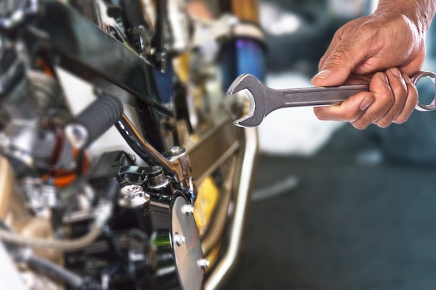 Photo hand with wrench, professional mechanic repair and modifications to motorcycle
