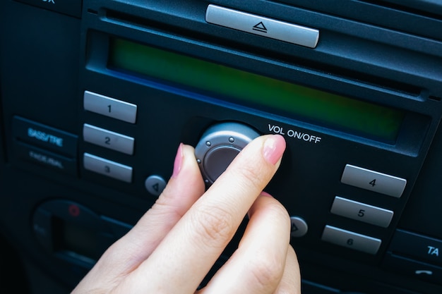 Foto mano di una donna sta accendendo il volume della radio in macchina