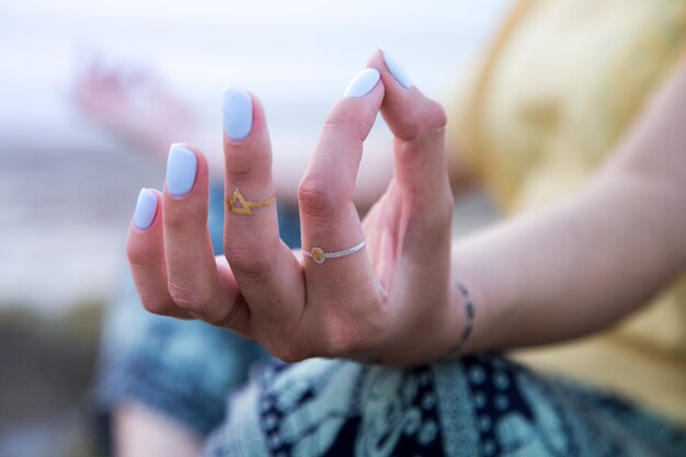 Hand of a woman meditating in a yoga pose on the beach at sunset