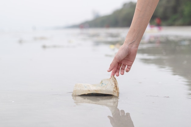 Hand woman picking up plastic cup cleaning on the beach