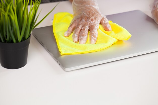 Hand of a woman wiping work desk, close-up.