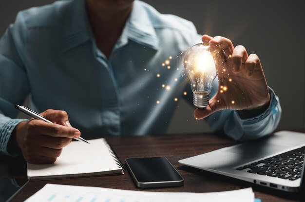 Hand of woman with light bulb and there is gear icon and using laptop computer Idea of inspiration from online technology Innovation idea concept Concept of brainstorming inspiration creatively