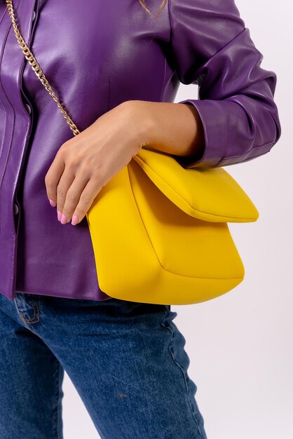 Hand of a woman with a yellow bag on a white background fashion studio