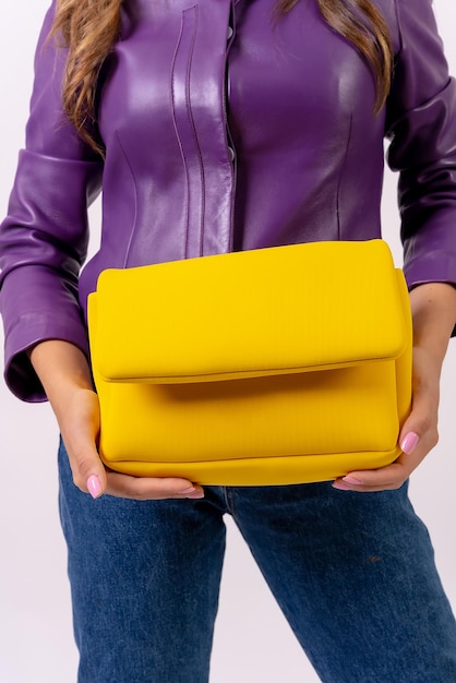 Hand of a woman with a yellow bag on a white background fashion studio