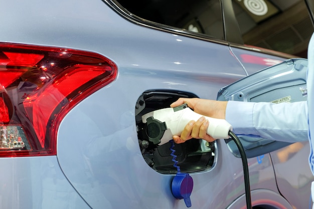 рука женщин, заправляющих новый автомобиль с помощью перезаряжаемой электрической машины