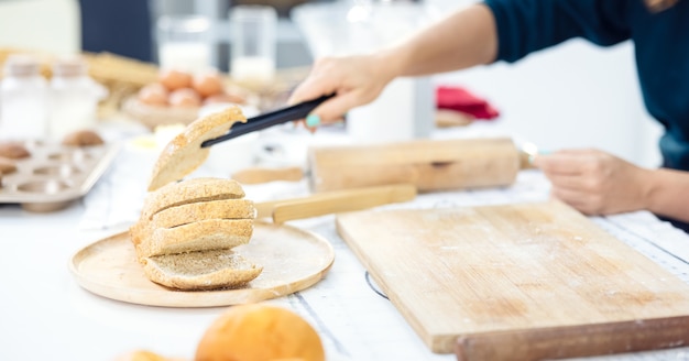 Руки женщины берут золотой кукурузный хлеб на кухне