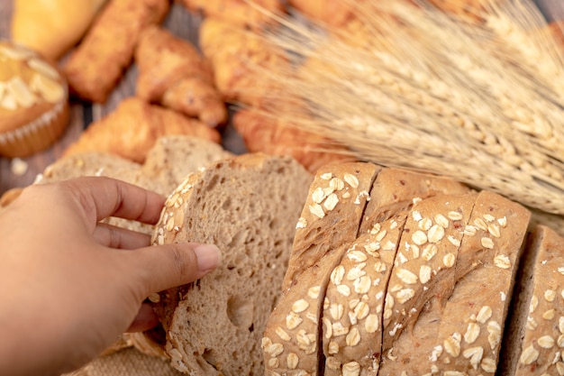 Рука женщины берут золотой кукурузный хлеб