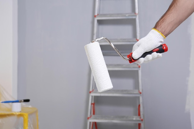 Hand of worker with paint roller in room