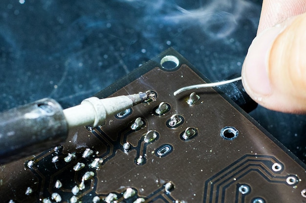 Hand working on a circuit board by soldering