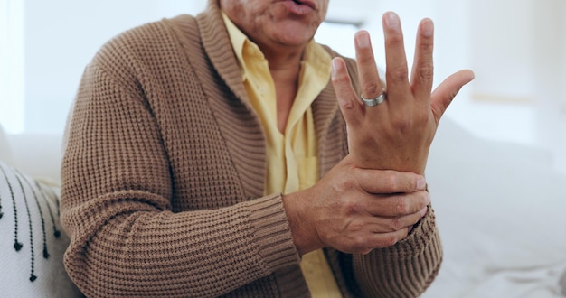 Foto dolore e lesione al polso della mano con una persona anziana su un divano nel soggiorno di una casa per massaggiare un'articolazione anatomia medica o dolore e un anziano nel suo appartamento con artrite o tunnel carpale