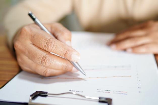 Hand write and work on paper sheet at table in office.