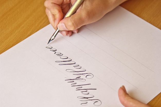 Foto la mano scrive con la penna inchiostro il felice halloween su un foglio di carta bianca con strisce di cancelleria sulla scrivania da vicino vista dall'alto lezioni di ortografia ed esercizi di calligrafia sfondo del layout del modello