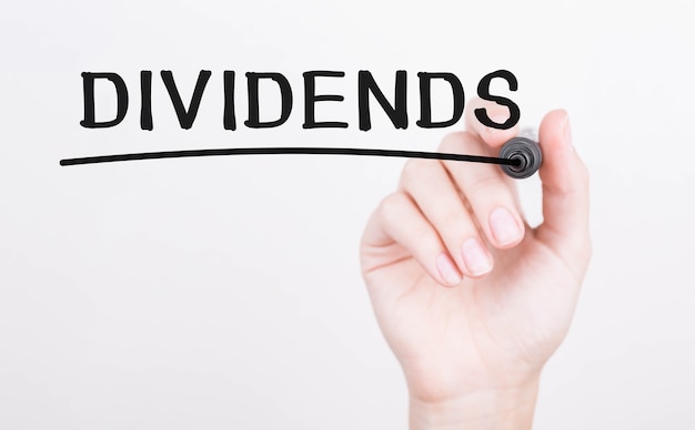 Hand writing Dividends with black marker on transparent wipe board.