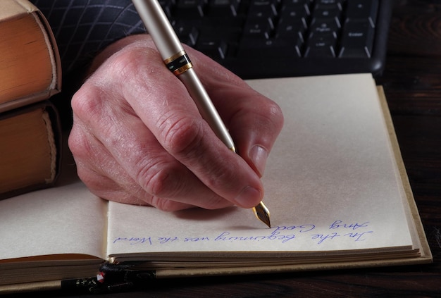 a hand writing on a notebook with a pen and a pen