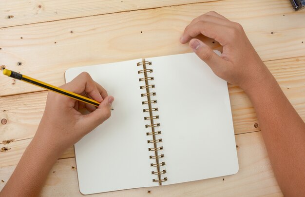 Hand on writing in notebook with wood backgroud