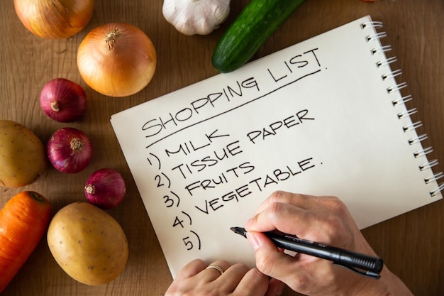 Photo hand writing a shopping list on wooden background