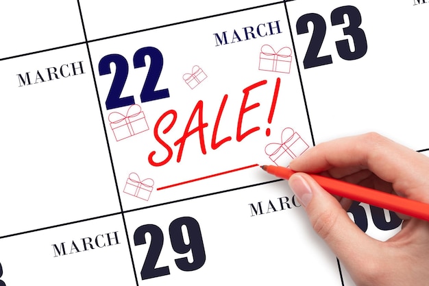 Hand writing text SALE and drawing gift boxes on calendar date March 22 Shopping Reminder