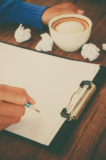 Foto mano che scrive con una tazza di caffè