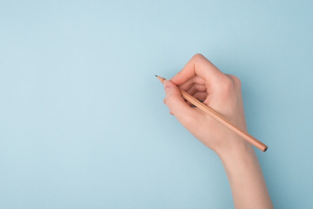 hand writing with a pencil on blue background