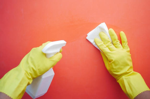 Hand in yellow rubber gloves holding spray bottle cleaning table
