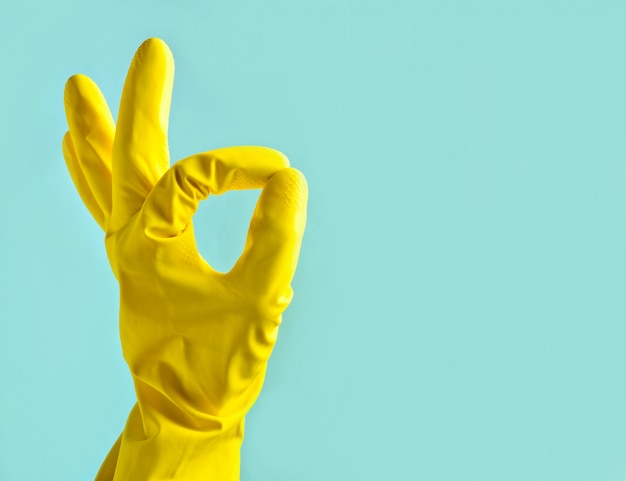 Hand in yellow rubber gloves shows thumbs symbol okay. Copy space