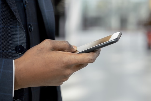 Hand of young african businessman scrolling in mobile phone