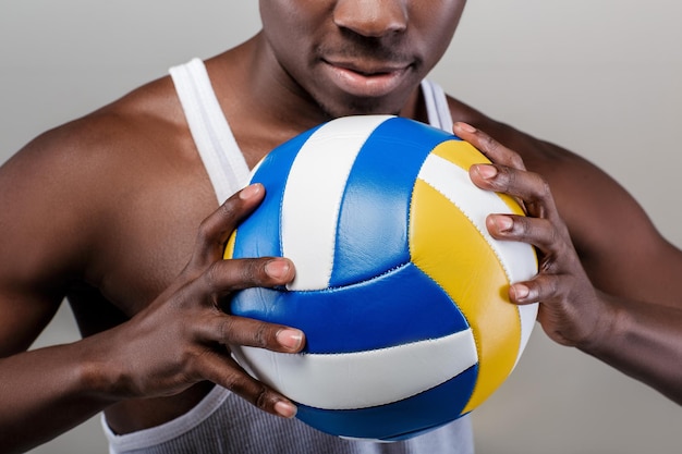 Mano di giovane uomo atletico afro-americano che tiene la palla da pallavolo, primo piano