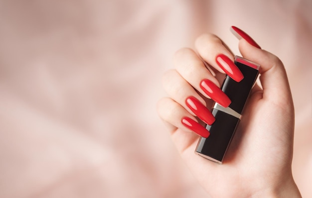 The hand of a young girl with a bright red manicure on her nails