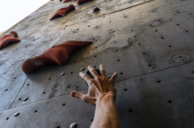 Hand of the young man on a hook of the artificial climbing wall