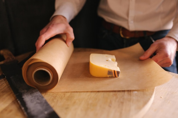 Hand of young man packing slice of cheese