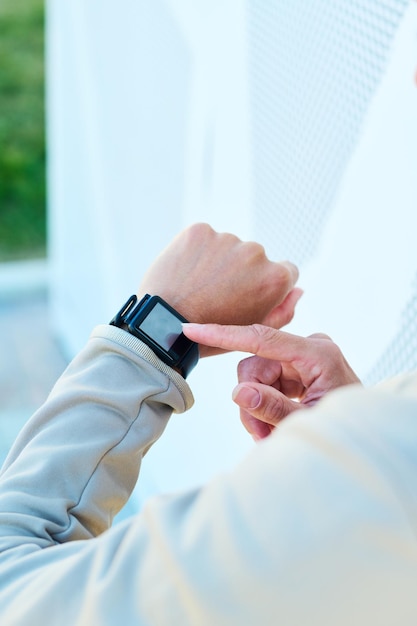 Hand of young modern sportswoman pointing at smartwatch on her wrist