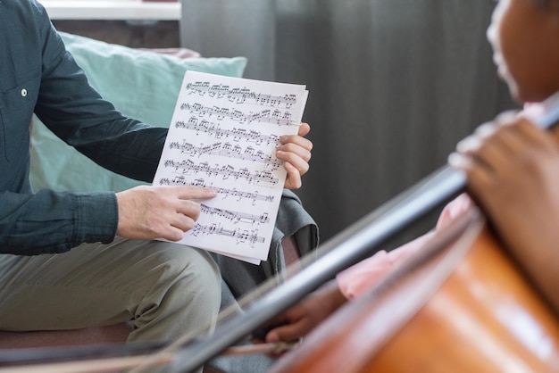 Foto mano del giovane insegnante di musica che indica il foglio con le note