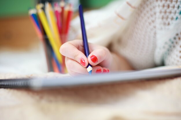 Hand of young woman drawing art picture by colorful crayons