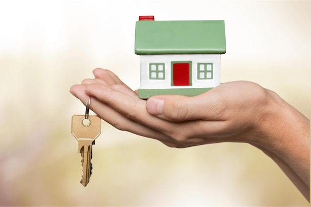 Hand of young woman holding little house model