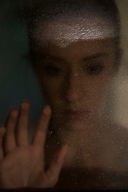 hand of young woman melancholy and sad at the window in the rain