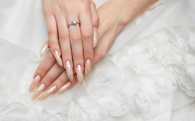 Hand of a young woman with white pearl manicure