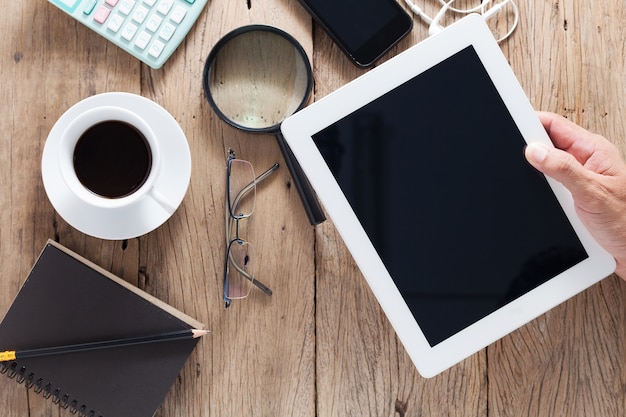 hand zakenman holding en gebruik tablet op houten bureau